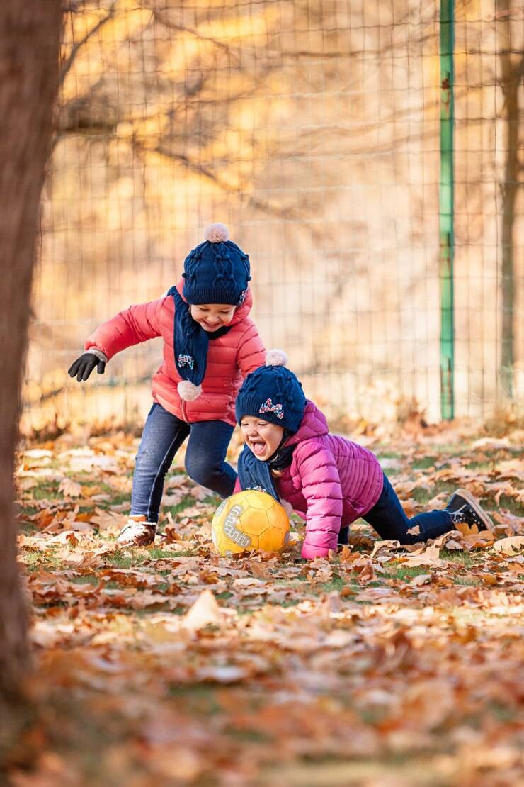 deklici se igrata z žogo v krajših otroških jaknah