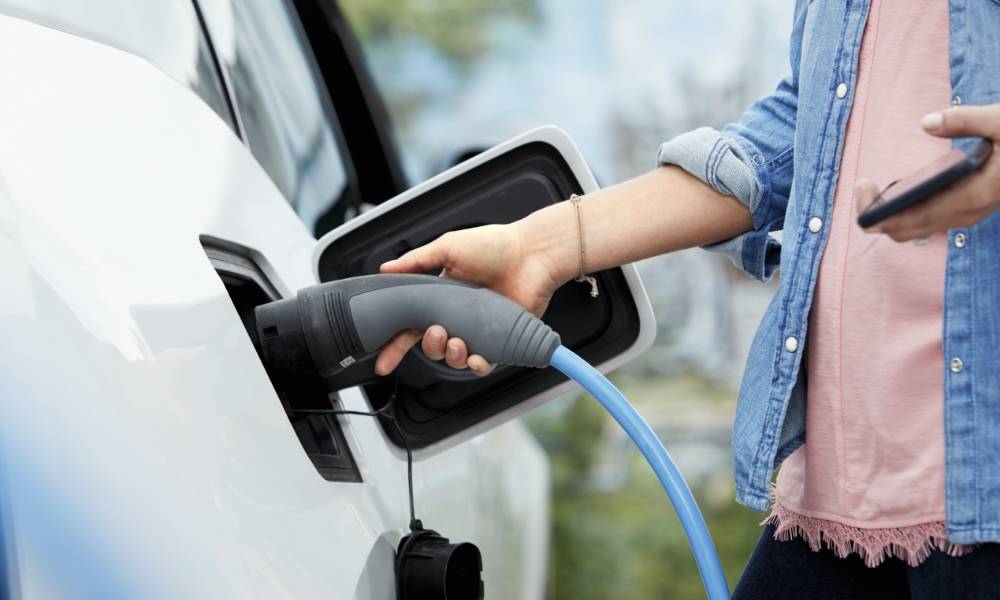 oseba polni električni avto